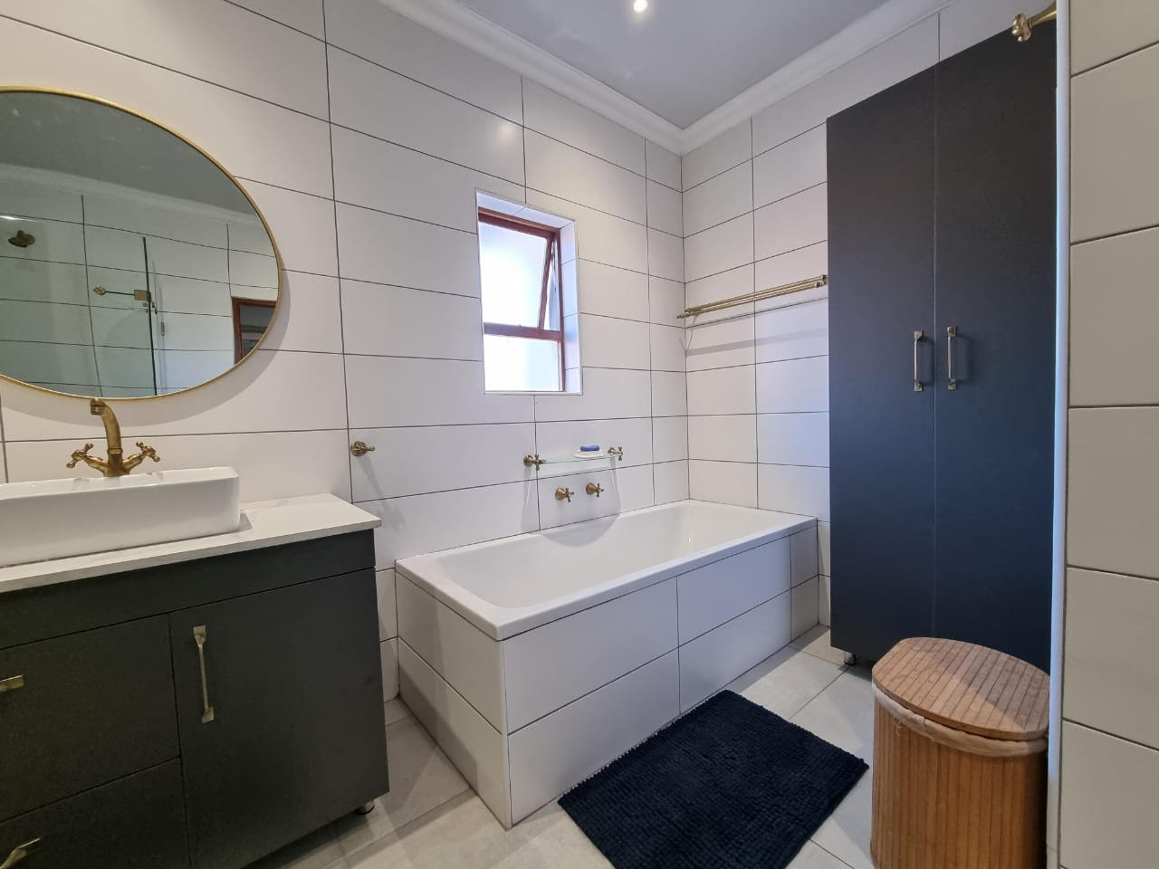 Renovated bathroom with bath vanity and round mirror