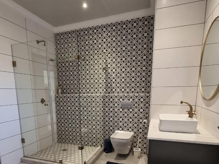 Bathroom renovation with glass shower and patterned feature wall