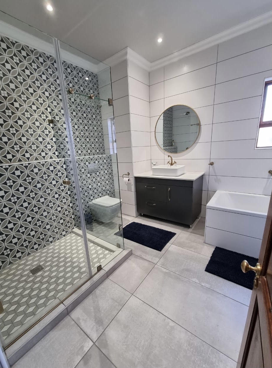 Completed bathroom renovation with patterned feature wall and glass shower by Bathroom Galore