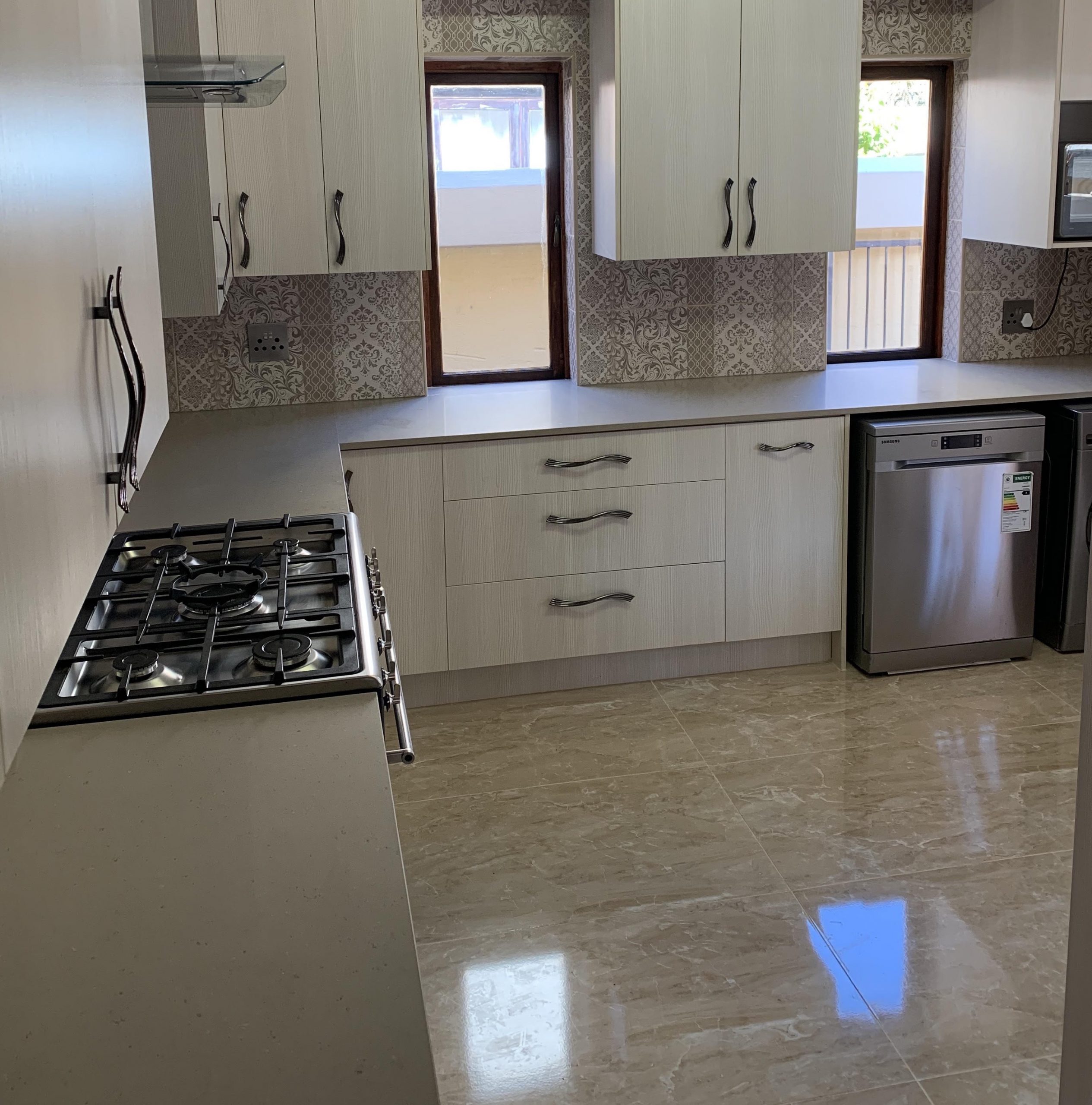 Light kitchen renovation with pale cabinetry and patterned splashback by Bathroom Galore