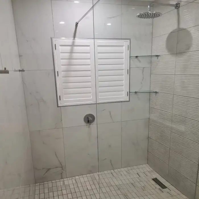 Completed bathroom renovation with glass shower and marble-look tiling by Bathroom Galore