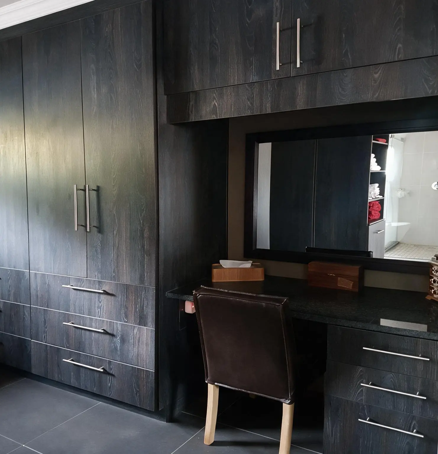 Dark woodgrain built-in bedroom cupboards with integrated dressing table and drawers by Bathroom Galore